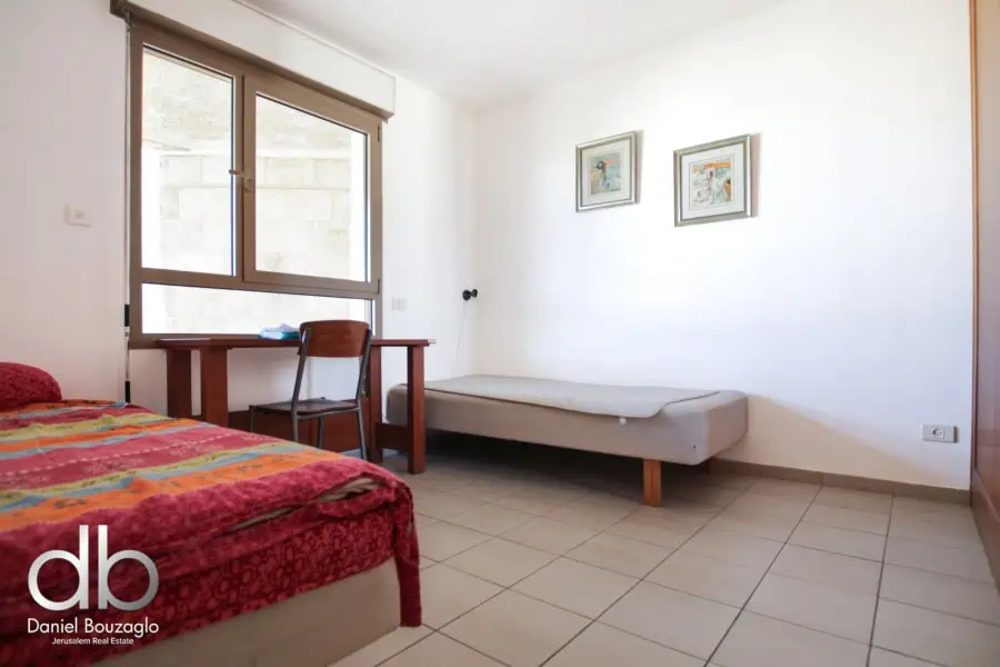 Modern Jerusalem real estate bedroom with large window, simple furniture, and minimal decor. Perfect for investors and homebuyers seeking prime property in Jerusalem.