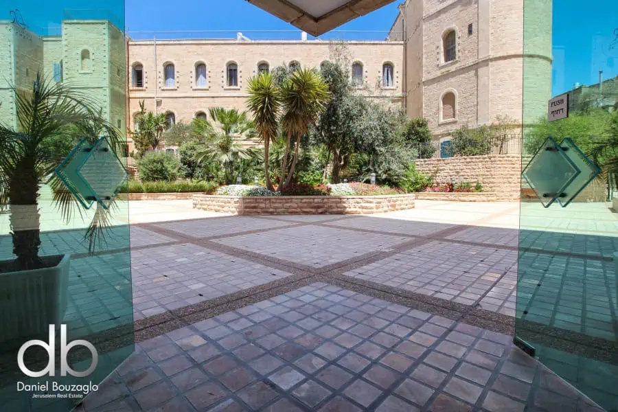 Modern Jerusalem courtyard with lush greenery and historic stone architecture, ideal for real estate investment or residential living, highlighted by Daniel Bouzaglo Jerusalem Real Estate.