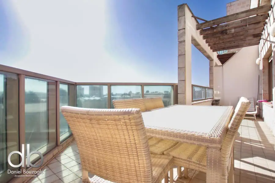 Balcony view of Jerusalem real estate property with outdoor dining furniture, spacious terrace, and modern design elements, ideal for lifestyle and investment in Jerusalem real estate.