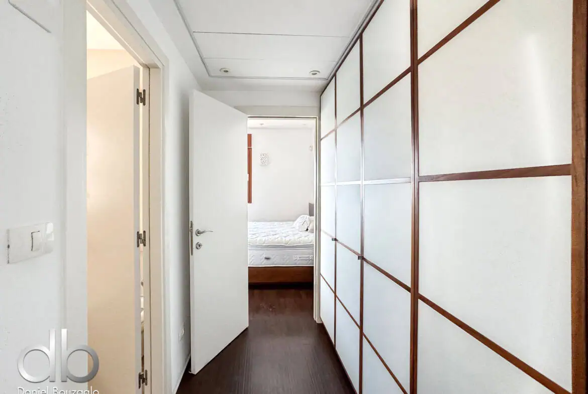 David Crown 25br furnished rental Jerusalem 14 Modern Jerusalem real estate interior with a hallway and bedroom view, showcasing stylish design, white walls, wooden accents, and excellent natural lighting.