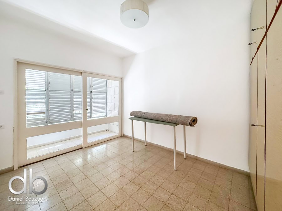 Bright Jerusalem real estate apartment interior with large glass doors, white walls, tiled flooring, and a minimal decor design, ideal for urban living or investment in Jerusalem properties.