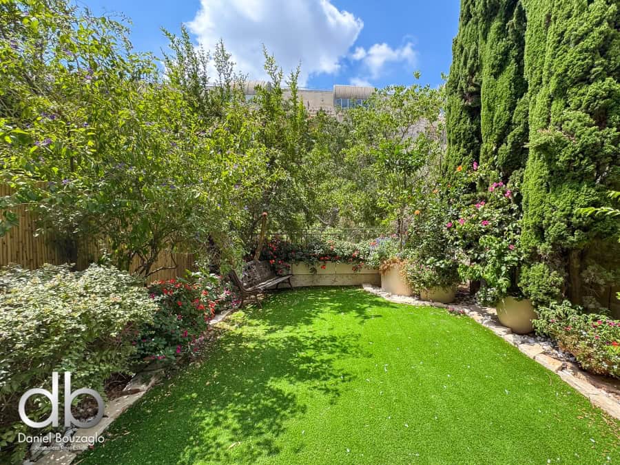 Garden apartment in David Village for sale 10 Lush backyard garden with vibrant greenery and blooming flowers in Jerusalem, Israel, perfect for real estate showcase and garden enthusiasts.