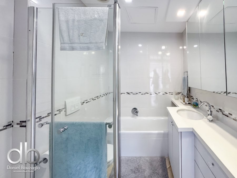 Garden apartment in David VIllage for sale 12 Modern Jerusalem bathroom with glass shower enclosure, bathtub, white cabinetry, and contemporary fixtures, perfect for Jerusalem real estate buyers seeking stylish, functional homes.