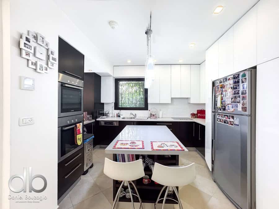 Garden apartment in David VIllage for sale 6 Modern Jerusalem real estate kitchen with black and white cabinets, stainless steel appliances, and cozy dining area, perfect for contemporary living in Jerusalem.
