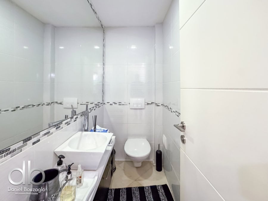 Garden apartment in David VIllage for sale 8 Modern Jerusalem real estate bathroom with white tiles and contemporary fixtures, ideal for buyers seeking sleek interiors.