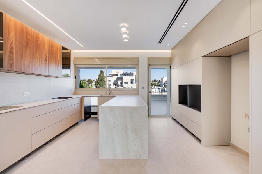 Harakevet rd duplex penthouse for sale 17_1 Modern Jerusalem real estate kitchen with minimalist design, sleek cabinetry, and ample natural light from large windows, ideal for contemporary living.