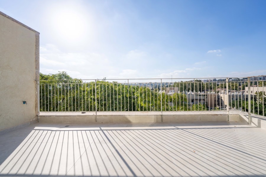 Harakevet rd duplex penthouse for sale 22_1 Spacious balcony overlooking Jerusalem cityscape with lush greenery under bright blue sky and sunlight. Ideal for real estate listings showcasing Jerusalem properties and scenic views.