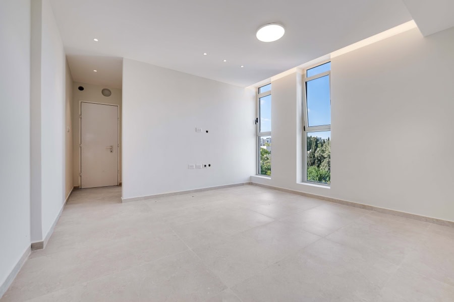 Harakevet rd duplex penthouse for sale 7_1 Modern Jerusalem real estate interior with bright white walls, large windows showcasing city views, and minimalistic design. Ideal for those seeking contemporary living spaces in Jerusalem.