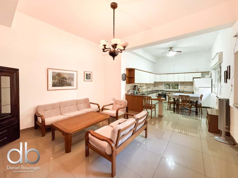 Bright living room with open kitchen in Jerusalem real estate listing by Daniel Bouzaglo, showcasing a cozy, modern space ideal for families and investors.