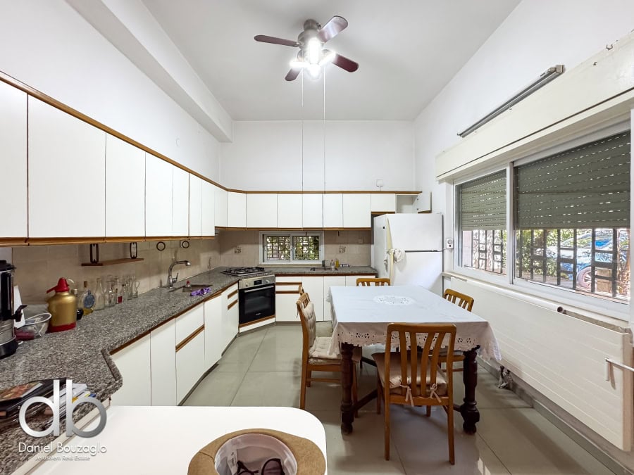 Bright kitchen in Jerusalem real estate listing with white cabinets and wooden accents, featuring a dining table, window view, and modern appliances. Ideal for homebuyers seeking Jerusalem properties.