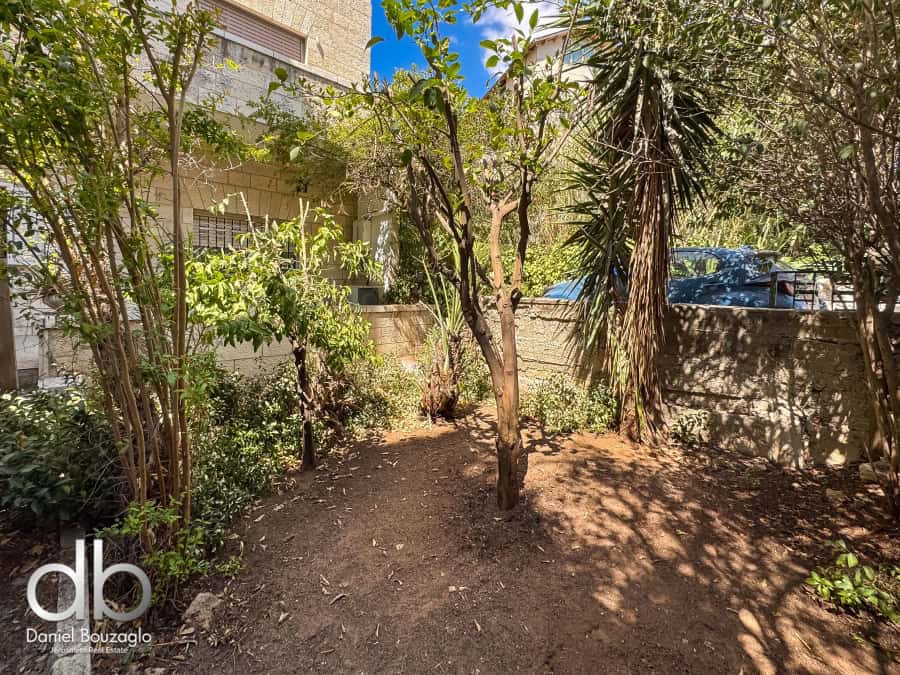 Lush private garden in Jerusalem with mature trees and vibrant greenery, ideal for relaxation or outdoor activities, showcasing desirable real estate features in the Jerusalem area.
