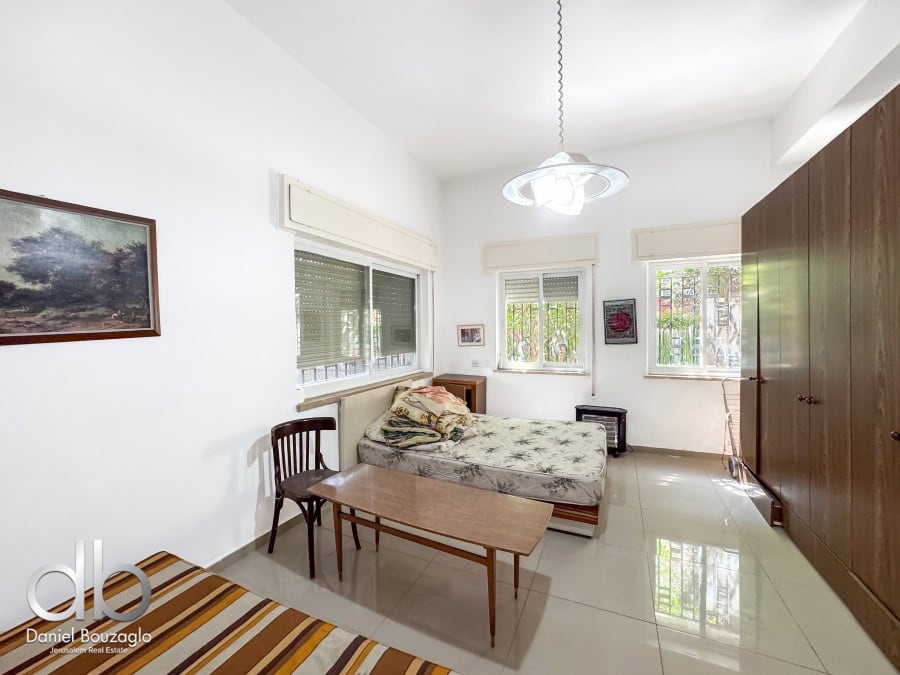 Sunny Jerusalem apartment interior with large windows, cozy bedroom, wooden furniture, and stylish decor — perfect for real estate investment or living in Jerusalem.