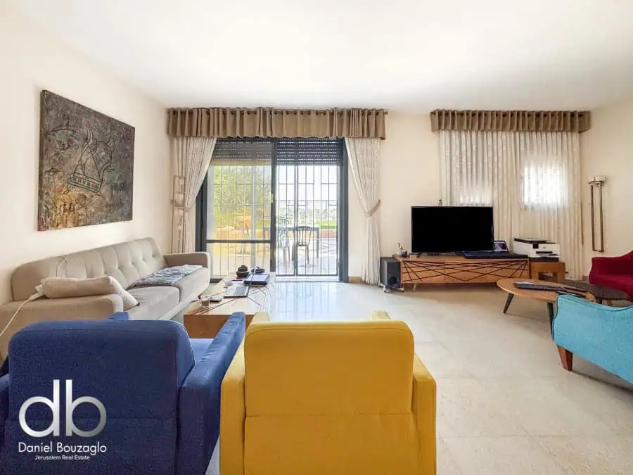 Colorful modern living room with large windows, comfortable furniture, and contemporary decor, showcasing Jerusalem real estate by Daniel Bouzaglo.