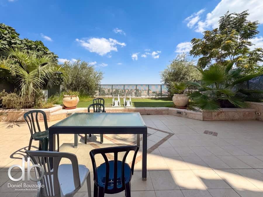 Balcony with outdoor seating, lush greenery, and panoramic Jerusalem city views, ideal for real estate showcasing in Jerusalem.