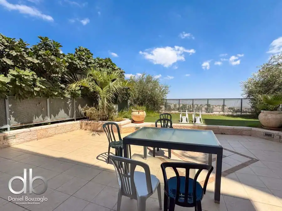 Modern Jerusalem rooftop terrace with outdoor dining area, lush greenery, aloe vera plants, and panoramic city views, ideal for Jerusalem real estate investment and lifestyle.