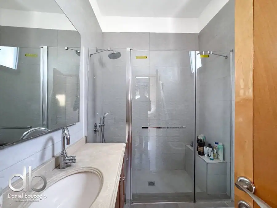 Modern Jerusalem real estate bathroom with walk-in shower, glass doors, and contemporary fixtures.