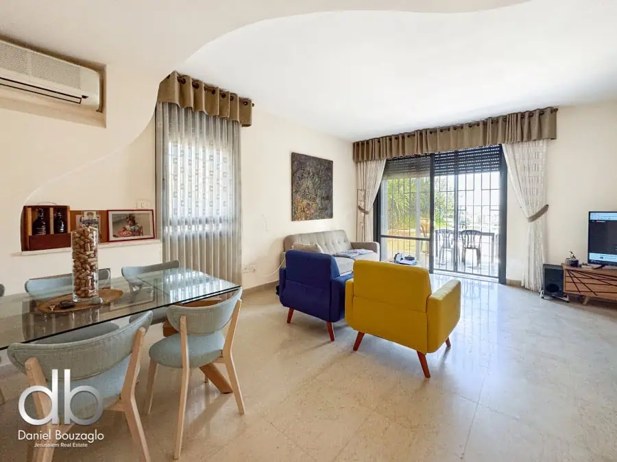 Bright Jerusalem real estate living room with colorful seating and large window featuring scenic views, ideal for comfortable city living.