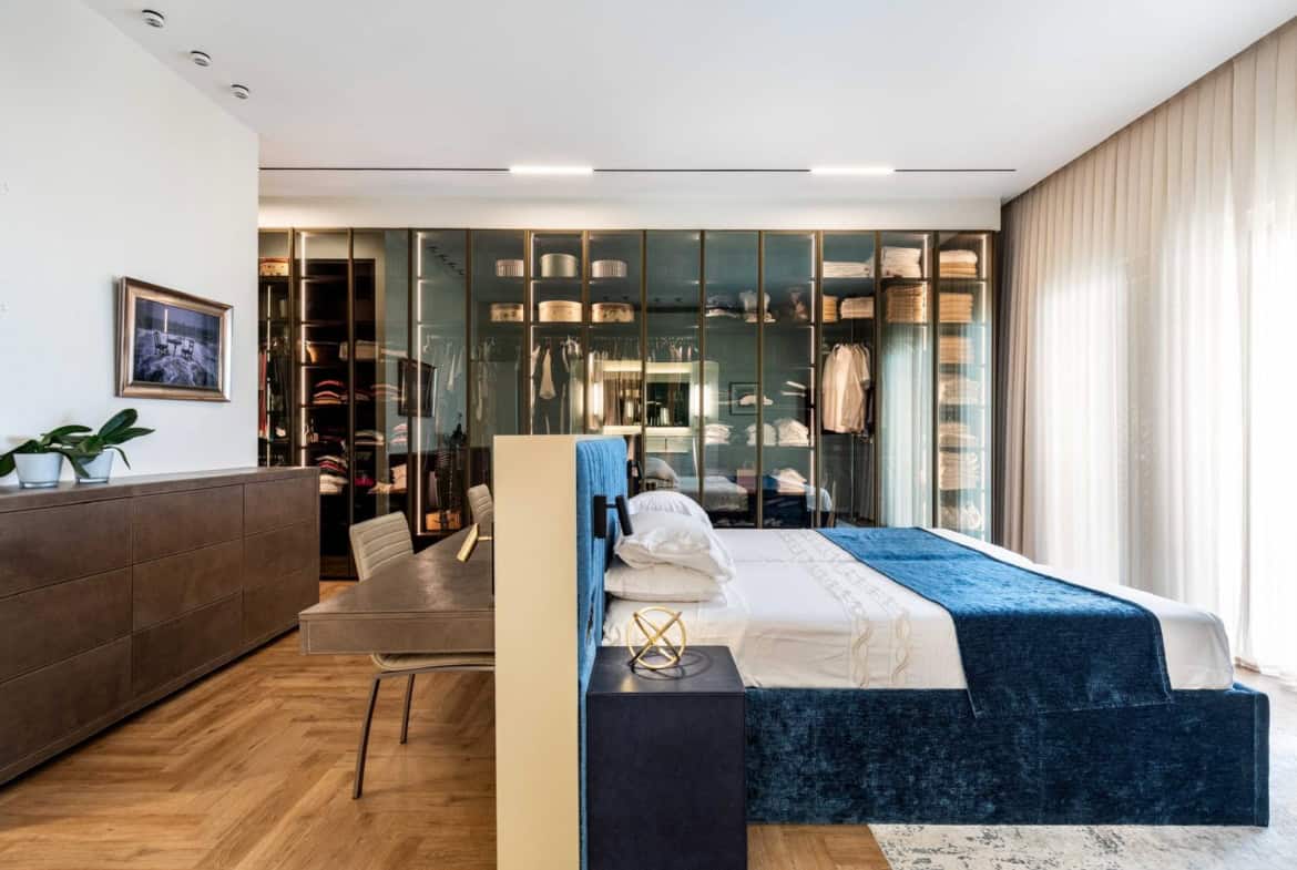 Stunning bedroom in Jerusalem real estate featuring a sleek, modern design, a stylish closet with glass doors, and abundant natural light, perfect for a luxurious living experience.