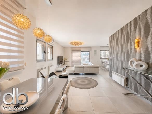 Open-concept living and dining area with white furniture, woven pendant lights, and a textured gray feature wall.