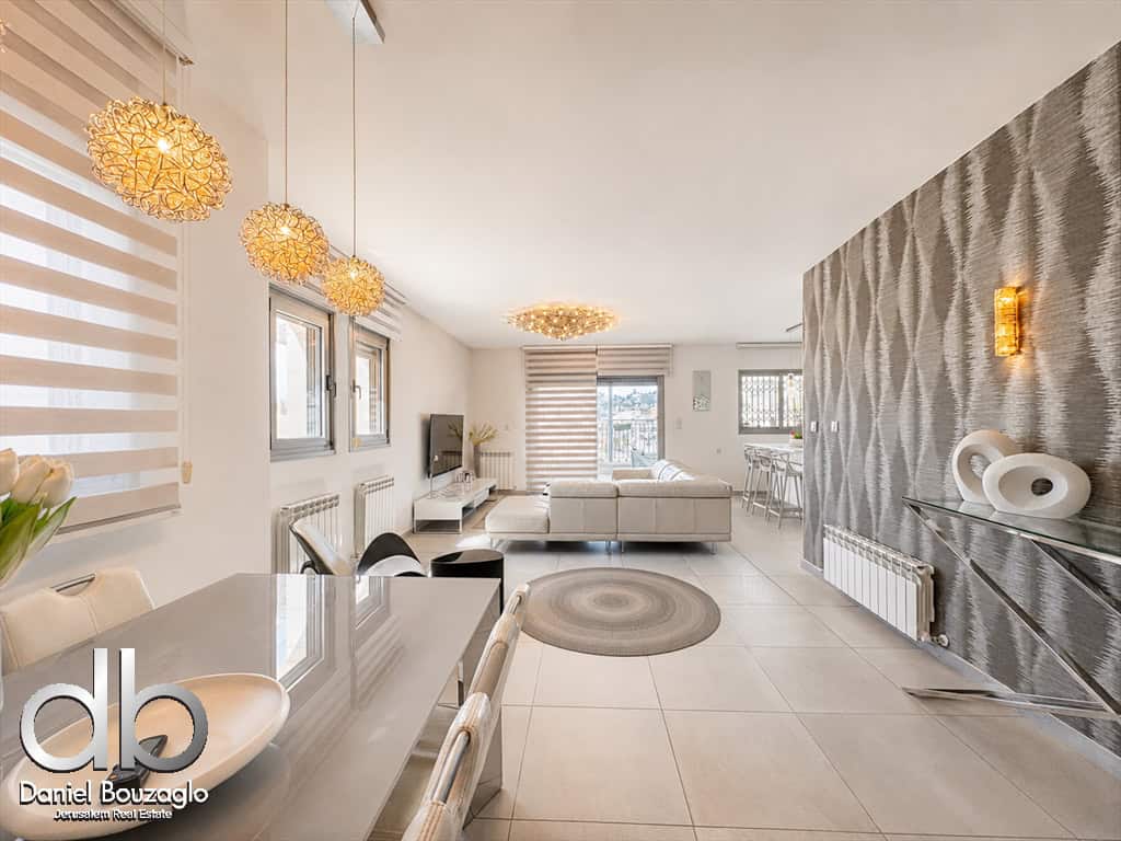 Open-concept living and dining area with white furniture, woven pendant lights, and a textured gray feature wall.