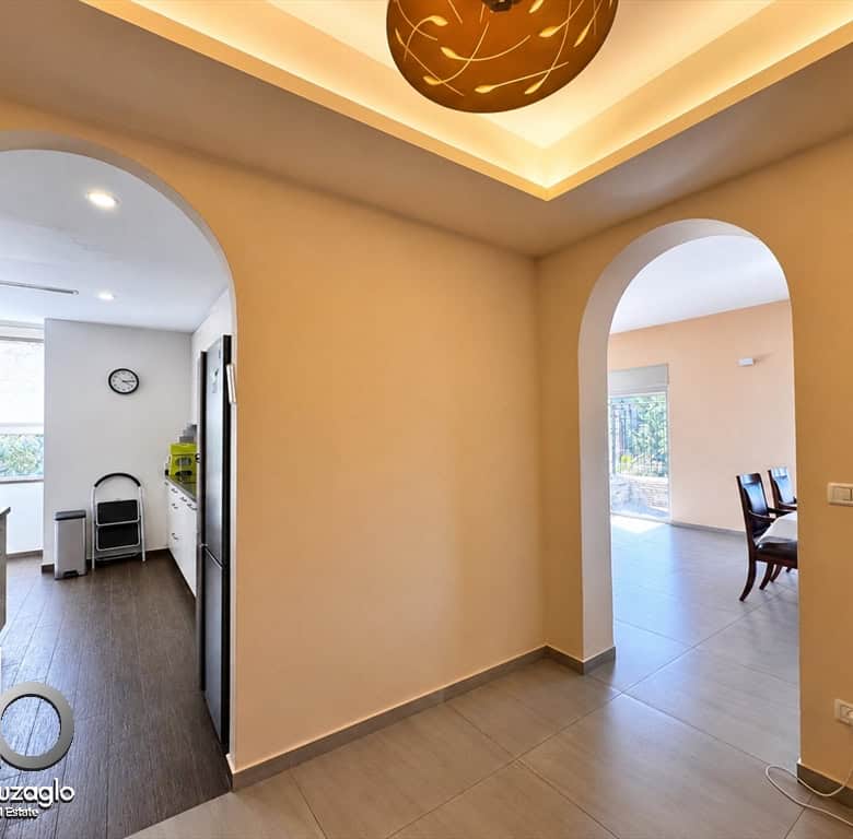 Interior entry area with two arched doorways: left to the kitchen, right to the dining room; warm ceiling lighting.
